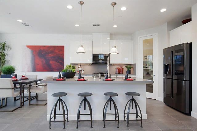 a kitchen with stainless steel appliances a table chairs refrigerator and microwave