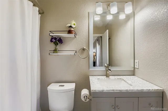 a bathroom with a granite countertop sink a toilet and mirror