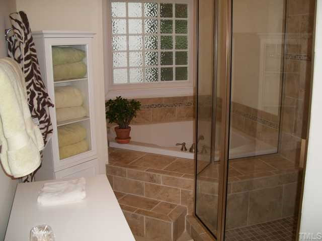8204 Dreamy Way Raleigh, NC 27613 - Photo 7 of 12 Sellers notice grout in their master bath was failing (due to incorrectly installed shower pan) they replaced EVERYTHING and the tile with this designer tile & tiled accents...satin nickle/brushed steel glass door is on the way.