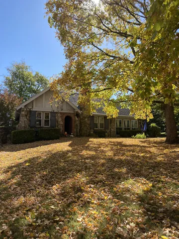 a front view of a house with a yard and tree