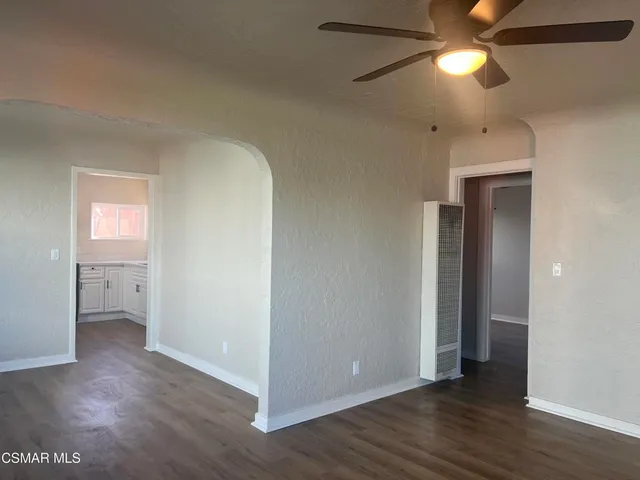 a view of an empty room with window and wooden floor