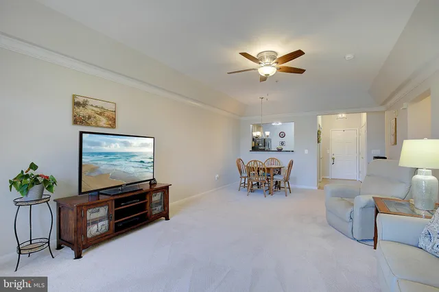 a living room with furniture and a flat screen tv with kitchen view