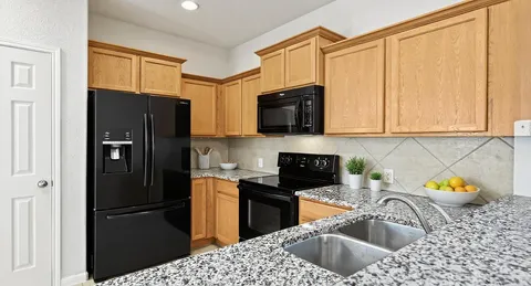 a kitchen with stainless steel appliances granite countertop a refrigerator a sink a stove a microwave and cabinets