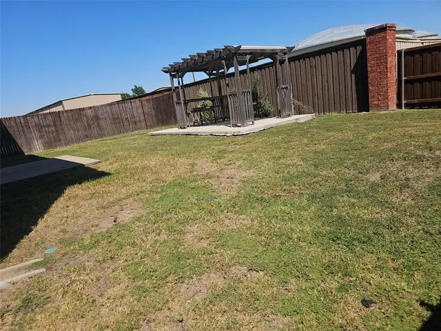 a view of a house with backyard and wooden fence
