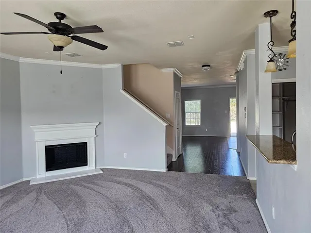 a view of a livingroom with a fireplace a chandelier a wooden floor and windows