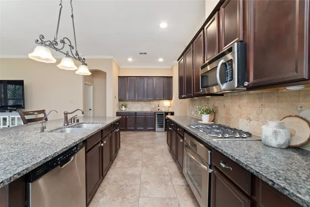 a kitchen with granite countertop stainless steel appliances a sink dishwasher a stove top oven a counter space and cabinets