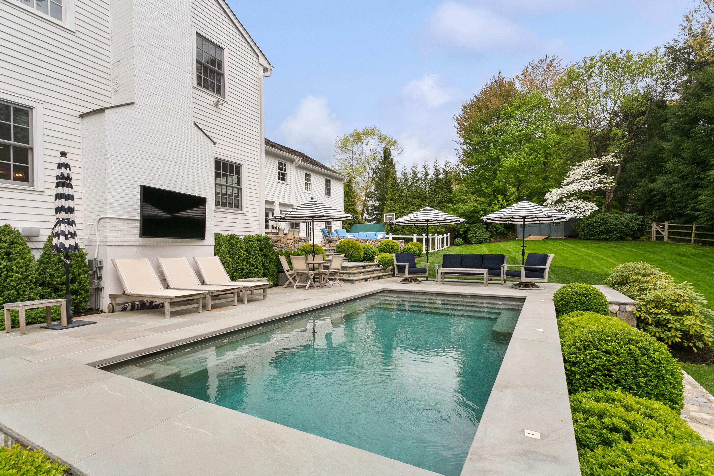 64 Summit Ridge Road New Canaan, CT 06840 - Photo 28 of 39 a view of a swimming pool with a table and chairs under an umbrella