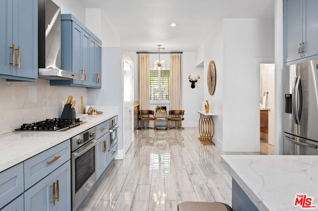 1083 East Circulo San Sorrento Road Palm Springs, CA 92262 - Photo 18 of 70 a kitchen with stainless steel appliances granite countertop a stove a sink dishwasher and a refrigerator with wooden floor