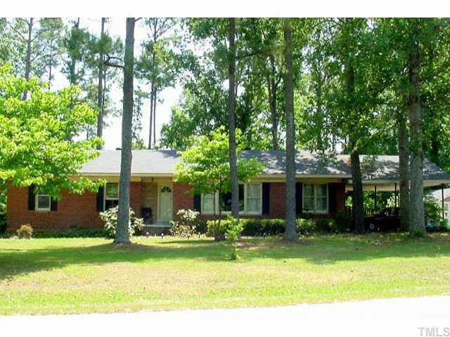 5317 Penny Road Raleigh, NC 27606 - Photo 1 of 1 Front of all brick home on .84 wooded acre w/greenhouse, storage out building, fruit trees & blueberry bushes and wheelchair ramp sheltered by oversized carport.