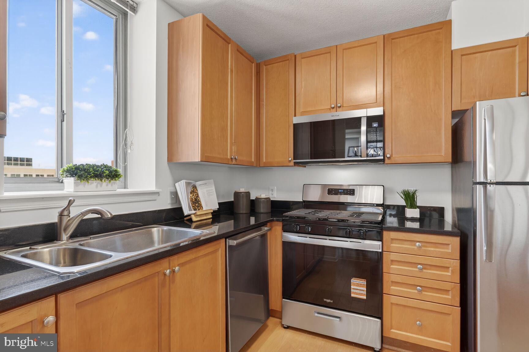 851 North Glebe Road, Unit 817 Arlington, VA 22203 - Photo 3 of 29 a kitchen with stainless steel appliances granite countertop a stove a sink and a microwave