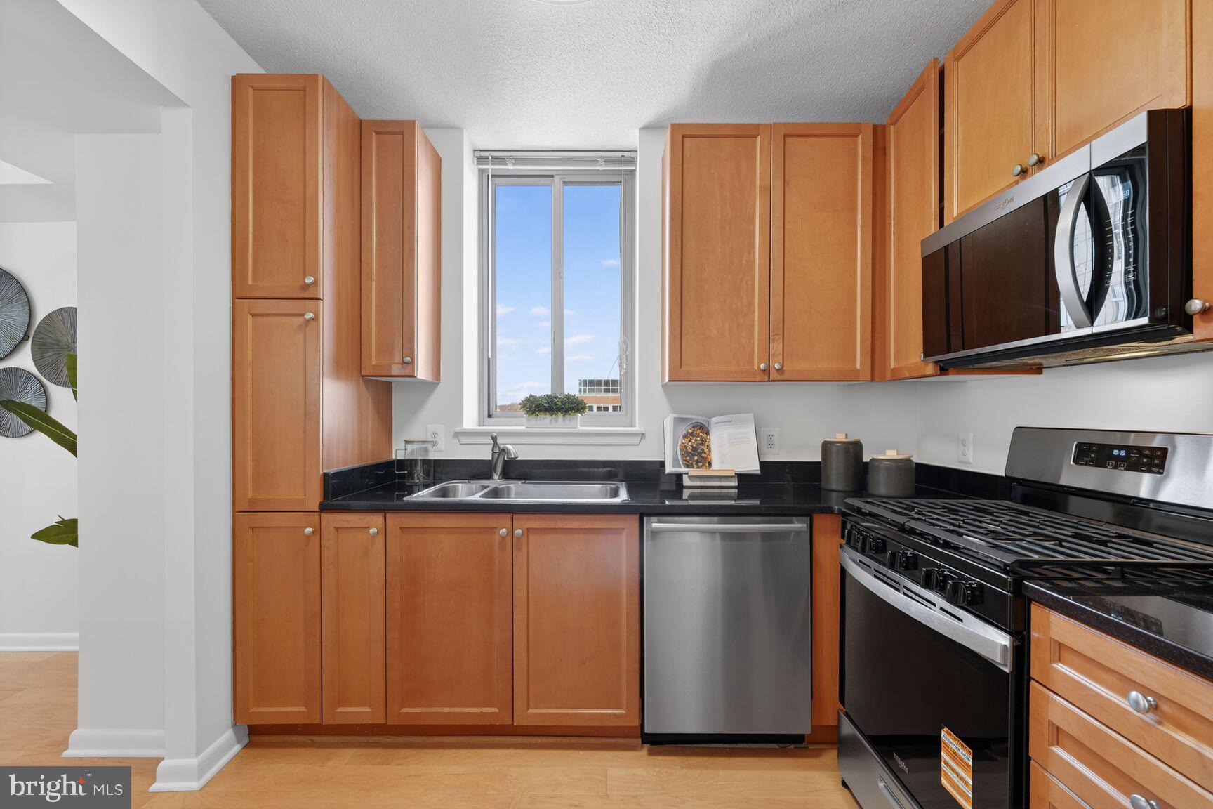851 North Glebe Road, Unit 817 Arlington, VA 22203 - Photo 4 of 29 a kitchen with stainless steel appliances granite countertop a stove a sink and a microwave