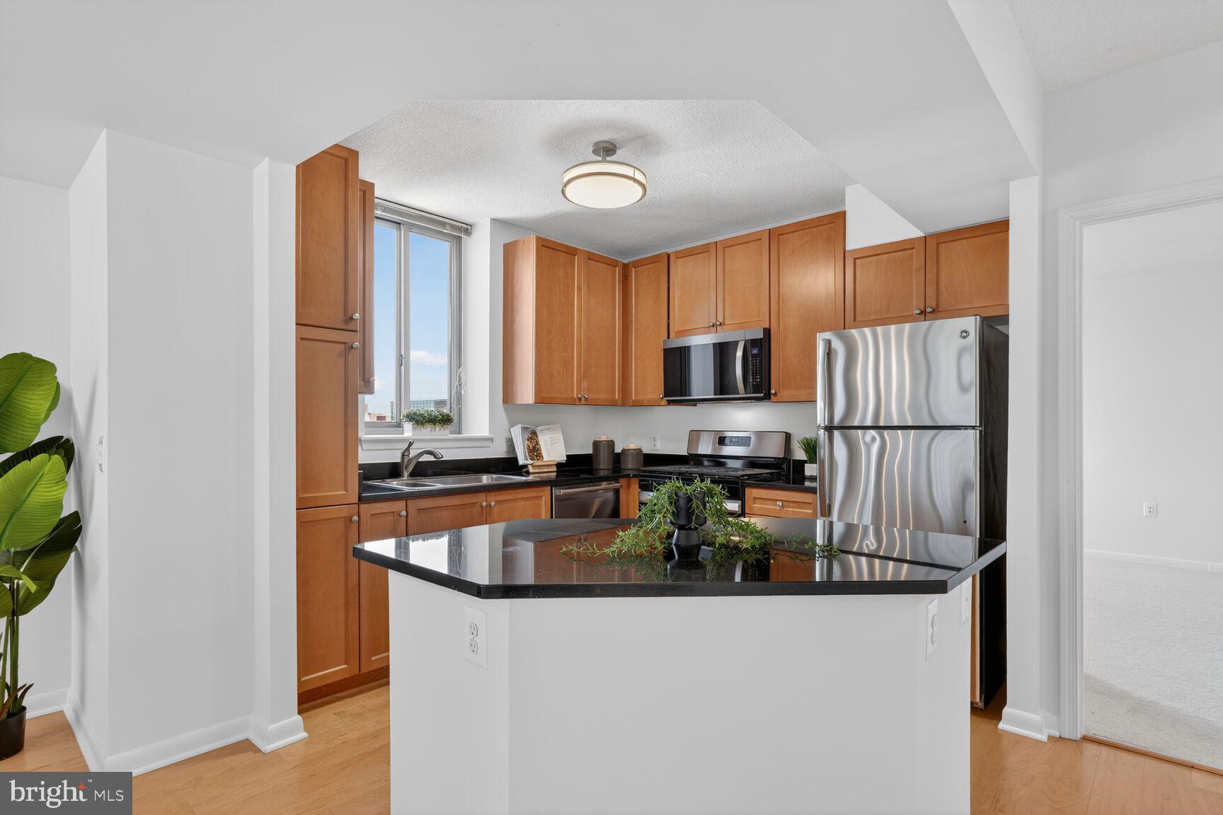 851 North Glebe Road, Unit 817 Arlington, VA 22203 - Photo 5 of 29 a kitchen with stainless steel appliances granite countertop a refrigerator a stove and a sink with wooden floor