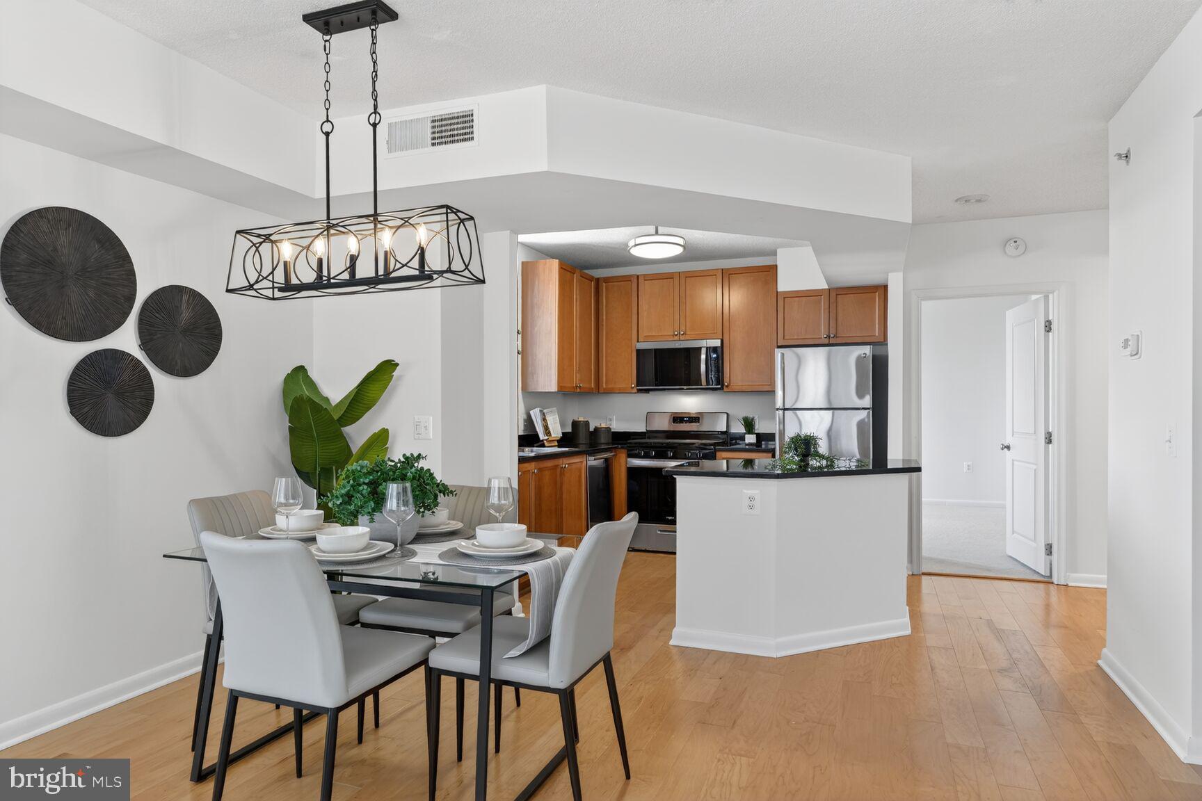 851 North Glebe Road, Unit 817 Arlington, VA 22203 - Photo 8 of 29 a kitchen with stainless steel appliances kitchen island granite countertop a table and chairs in it