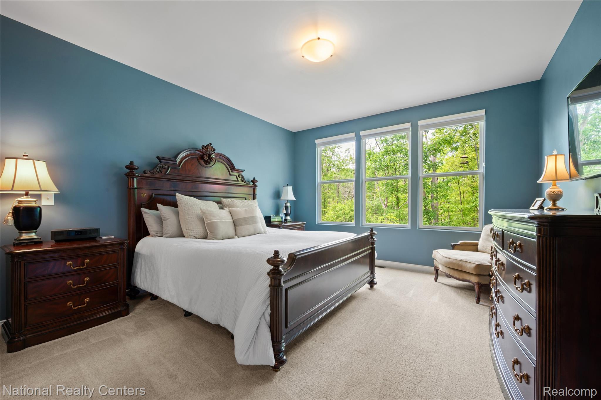 48796 Windfall Road Novi, MI 48374 - Photo 14 of 30 Light-filled room featuring three large windows, carpet flooring, a ceiling-mounted light fixture, and rich blue wall paint