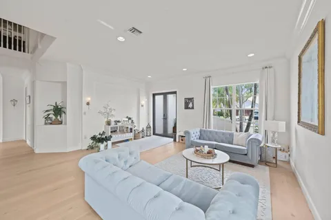 a view of a dining room and livingroom with furniture wooden floor a rug a painting and a chandelier