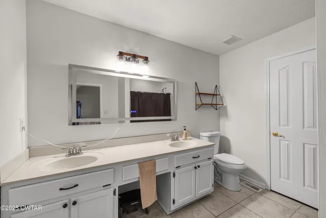 a bathroom with a double vanity sink mirror and toilet