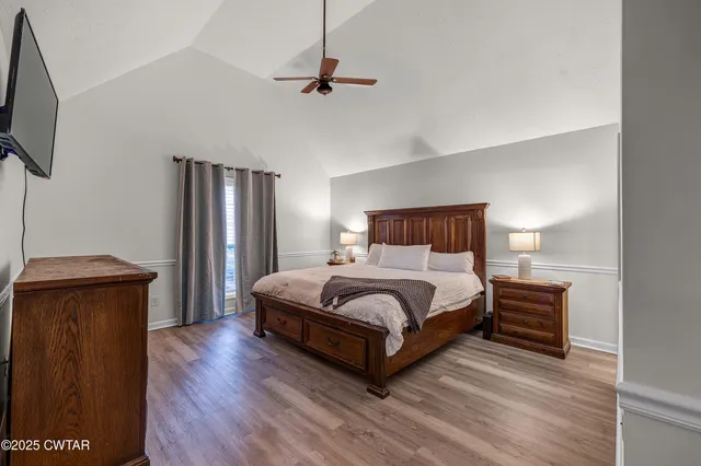 a bedroom with a bed a mirror on dresser and a wooden floor