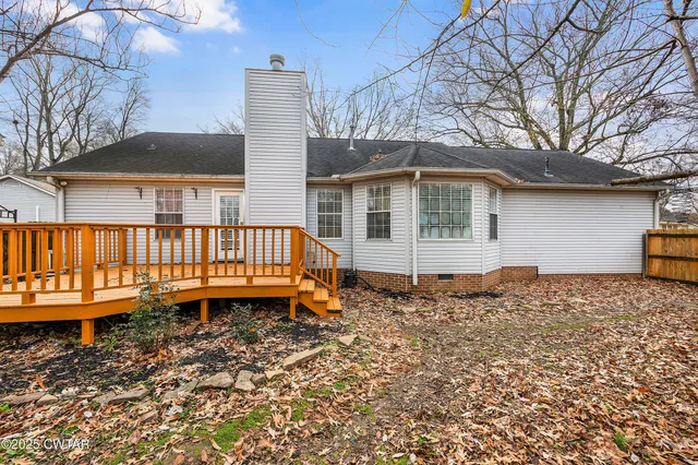 a backyard of a house with large trees and wooden fence