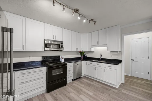 a kitchen with granite countertop white cabinets and stainless steel appliances