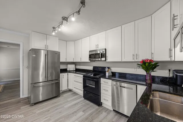a kitchen with white cabinets stainless steel appliances and a potted plant