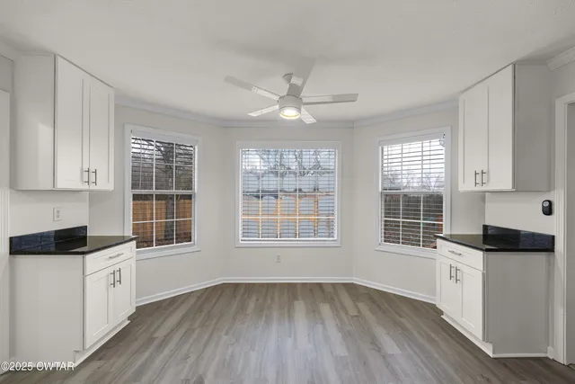 a view of an empty room with a kitchen and a window
