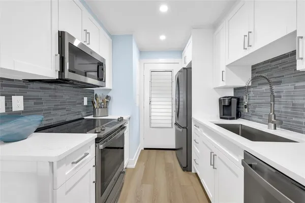 a kitchen with a sink a microwave a refrigerator and cabinets