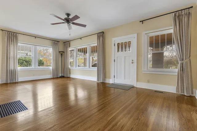 a view of an empty room with a window and wooden floor