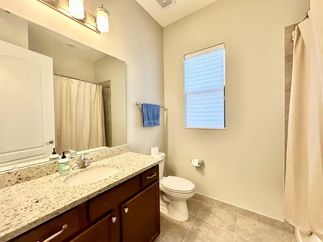 a bathroom with a granite countertop sink a toilet and a mirror