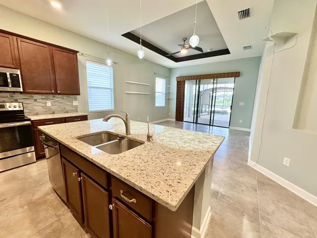 a kitchen with stainless steel appliances granite countertop a sink window and cabinets