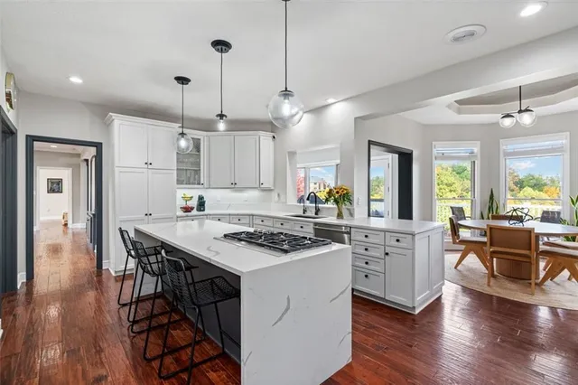 a kitchen that has a table chairs stainless steel appliances and wooden floor