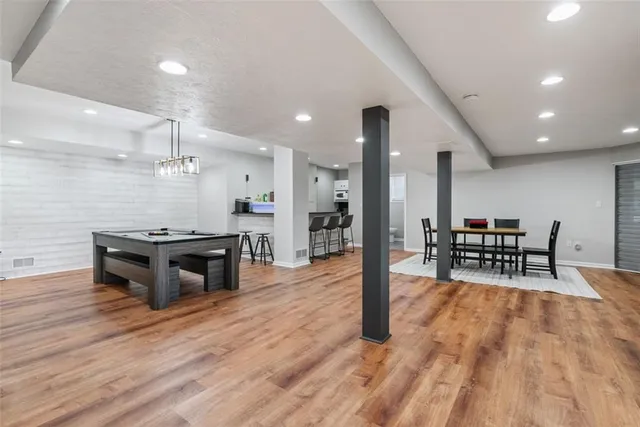 a kitchen with stainless steel appliances kitchen island granite countertop a table chairs and a wooden floor