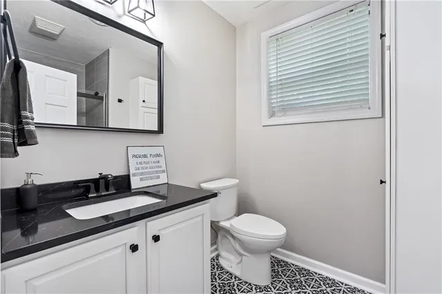 a bathroom with a granite countertop sink mirror vanity and toilet
