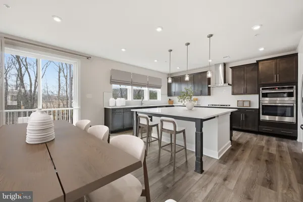 a kitchen with stainless steel appliances kitchen island granite countertop a stove a sink a microwave a dining table and chairs