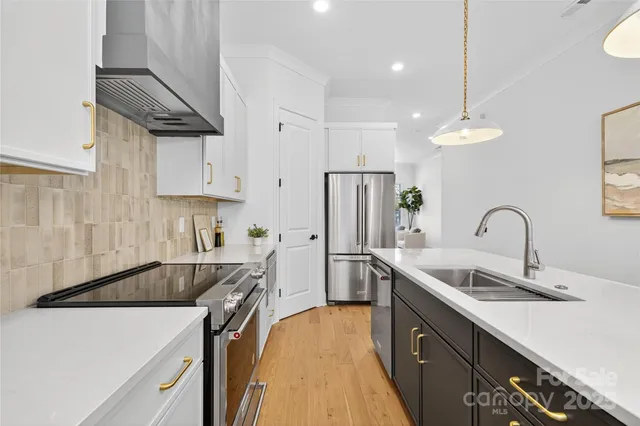 a kitchen with stainless steel appliances a sink a stove a refrigerator and cabinets