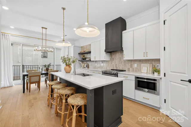 a kitchen with a stove a sink a kitchen island with chairs and wooden floor