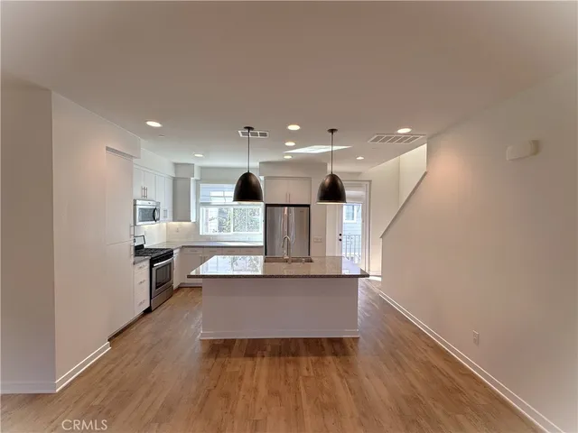 a kitchen with cabinets stainless steel appliances and wooden floor