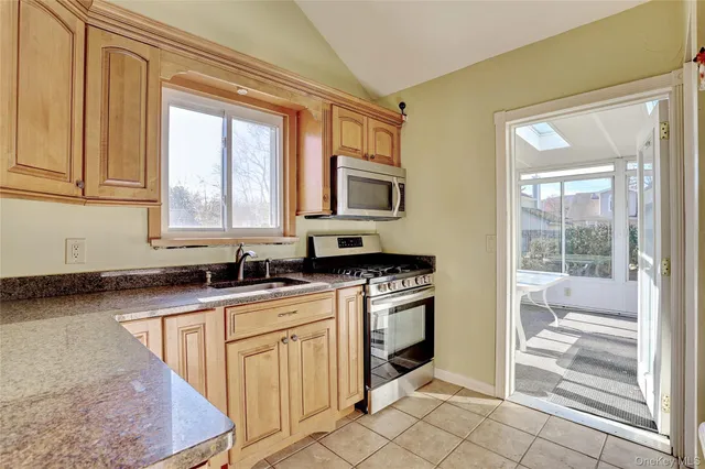 a kitchen with stainless steel appliances granite countertop a stove a sink and a microwave