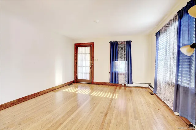 a view of an empty room with glass door and wooden floor