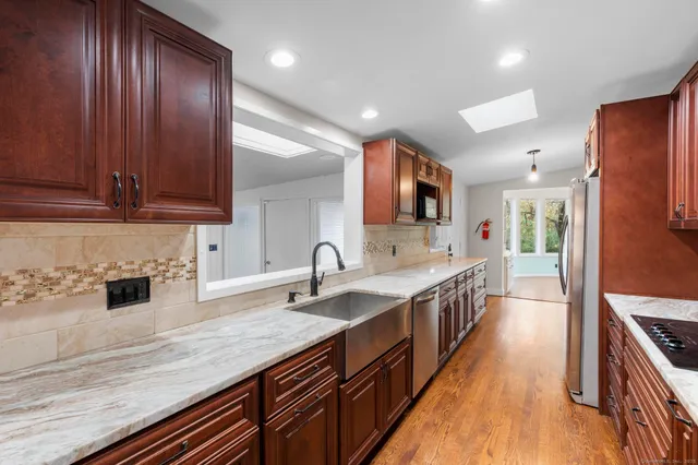 a kitchen with stainless steel appliances granite countertop a sink a stove and a wooden floors