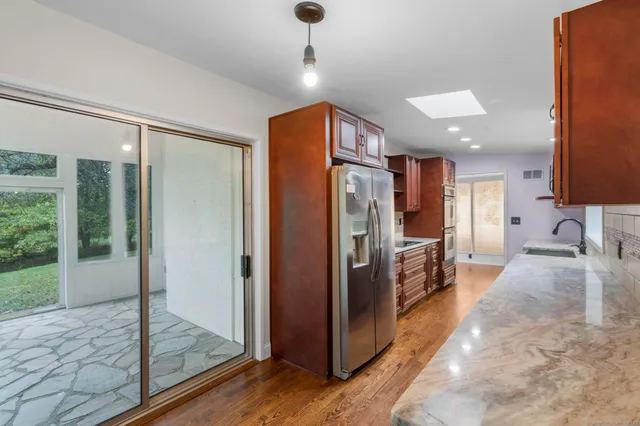 a open kitchen with stainless steel appliances granite countertop a refrigerator a oven and a sink with granite countertops