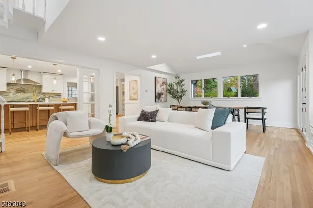 a living room with couches a coffee table and kitchen view with wooden floor