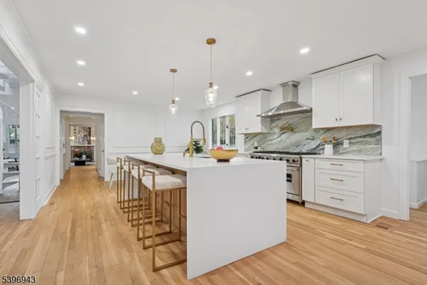 a kitchen with stainless steel appliances kitchen island granite countertop a stove a sink a refrigerator and white cabinets with wooden floor