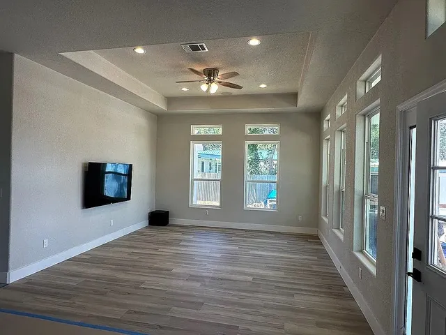 a view of kitchen and empty room with wooden floor