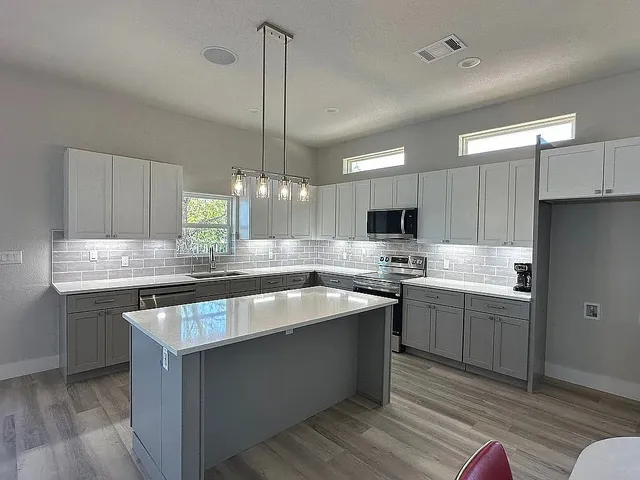 a large kitchen with stainless steel appliances a large counter top a sink a stove and a refrigerator