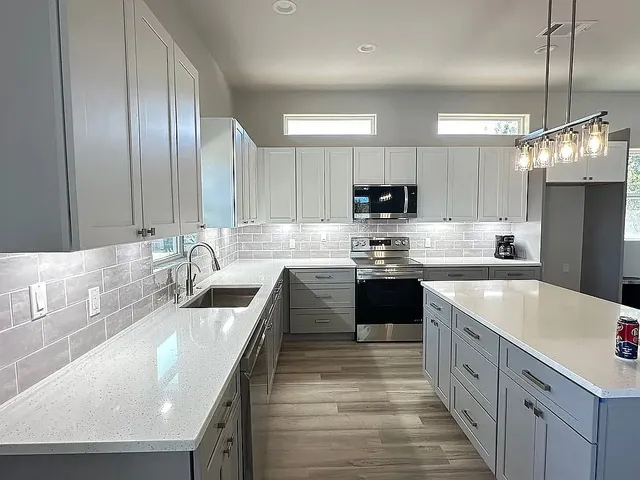 a large kitchen with stainless steel appliances granite countertop a sink a stove and a refrigerator