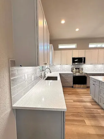 a kitchen with stainless steel appliances a sink a stove a microwave a center island and cabinets