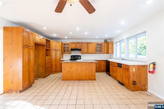 a large kitchen with stainless steel appliances kitchen island granite countertop a refrigerator a stove a sink and a window