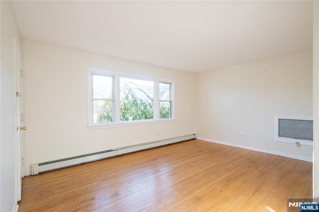 163 Bell Avenue, Unit 1 Lodi, NJ 07644 - Photo 5 of 12 an empty room with wooden floor and windows