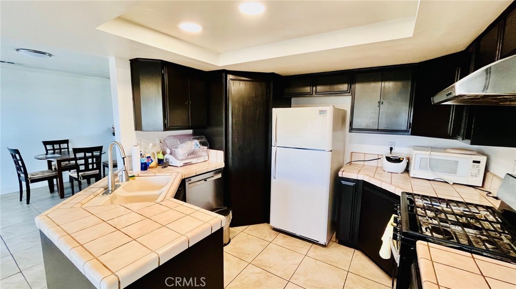 11911 Kiowa Road Apple Valley, CA 92308 - Photo 16 of 40 a kitchen with a refrigerator a stove a sink and a dining table