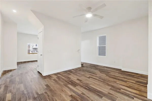 an empty room with wooden floor chandelier fan and windows